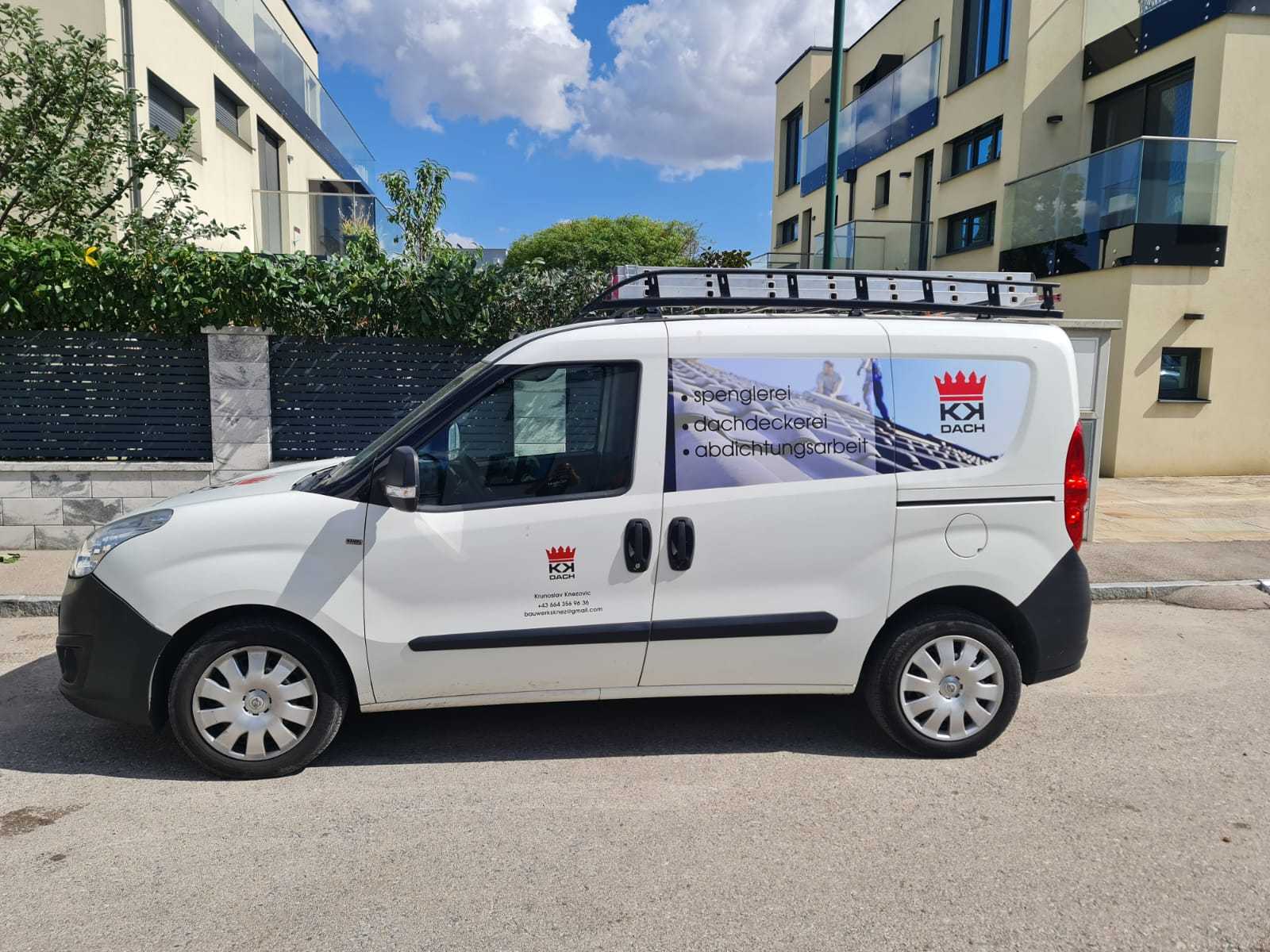 Weißer Firmenwagen von KK Dach mit Logo, seitlich vor einem Wohnhaus